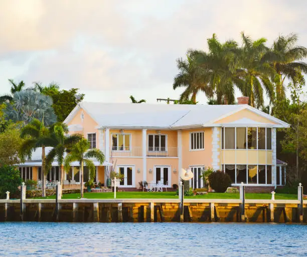 Peach waterfront home with crisp white exterior paint, trim, and finishes by a house painter in Fellsmere, FL.